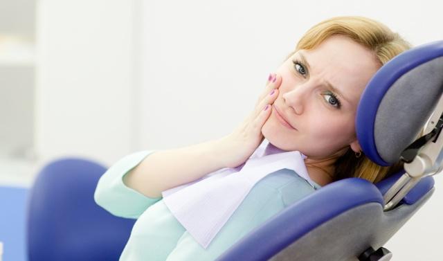 patient woman at the dentist complains of toothache. Looking at camera.