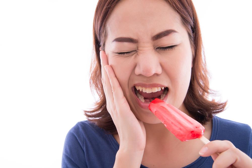 Women with sensitive teeth eating a popsicle