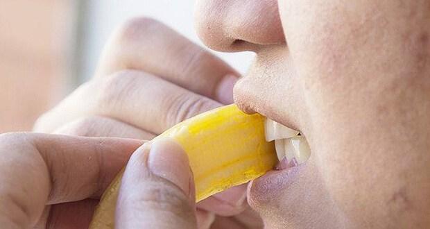 Woman whitening teeth with a banana peel