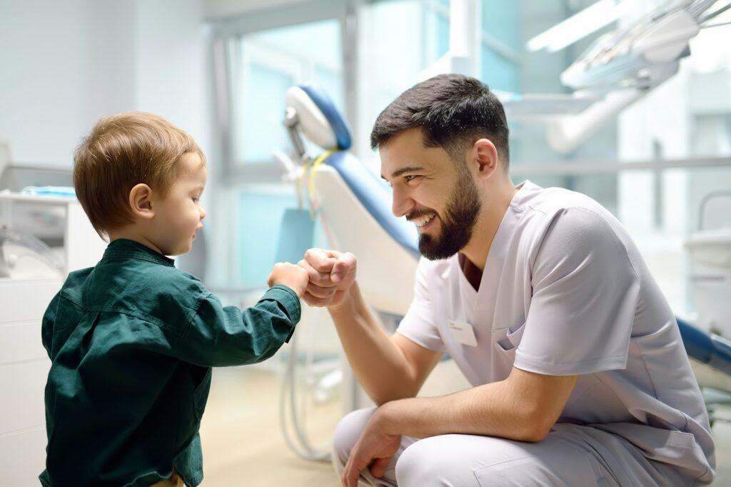 Friendly dentist greets cute toddler boy in office.