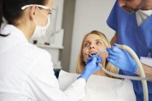 Stomatologist and her assistant treating woman for dental cavity