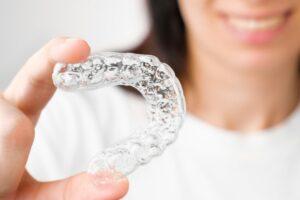 Close up orthodontic transparent aligner in womans hand. Removable braces