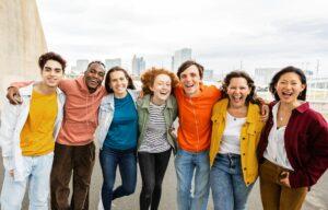 Happy group of teen friends hugging each other smiling at camera outside