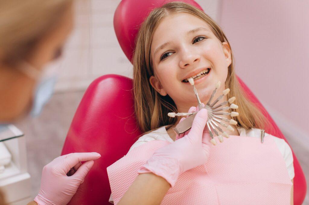 The dentist selects the color of the dental crown of a teenage girl in a dental clinic