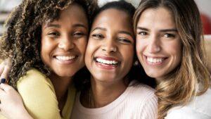 Three beautiful smiling girl friends hugging together