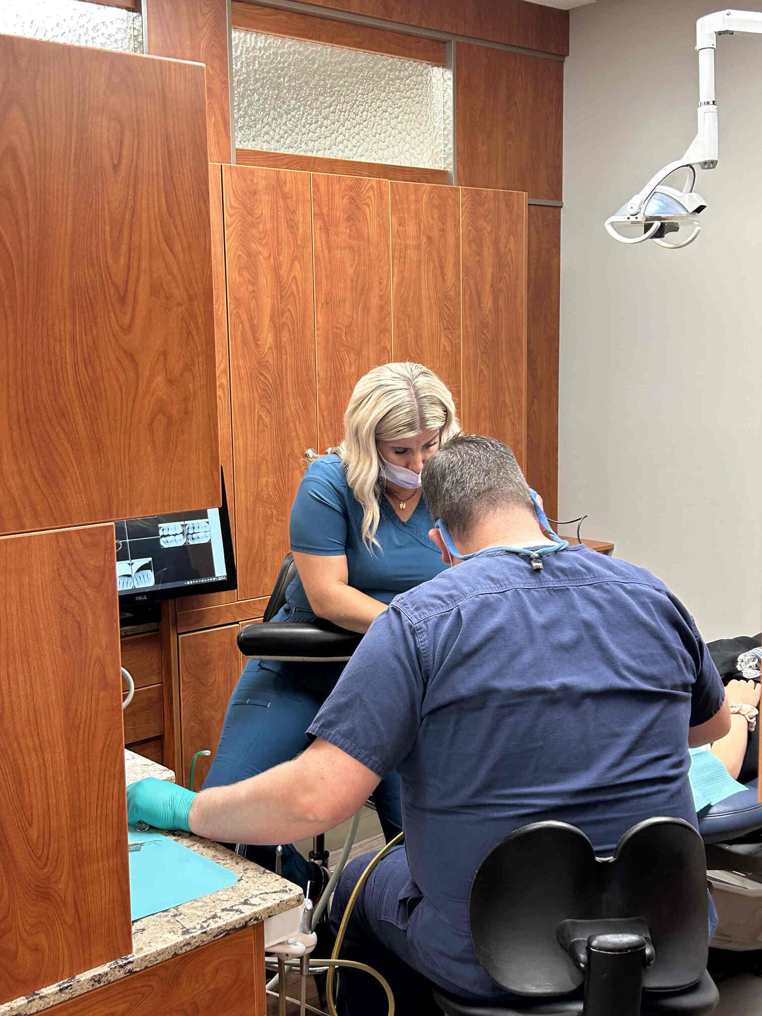 Patient holding their cheek with a toothache while waiting in a modern emergency dental office in Orem, Utah.