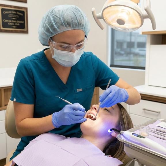 A Canyon Gate Dental dentist in Orem Utah placing a tooth-colored composite resin filling on a patient during a same-day restorative appointment